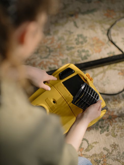 A cleaner, dressed in a light-colored jumpsuit, is operating a vacuum or extraction cleaning machine on a dark carpeted floor in a room with black paneled walls and a black radiator. The room has a white ceiling with a large white panel or screen mounted above. The floor appears to be under deep cleaning or sanitisation, with the equipment suggesting professional surface cleaning. Visible tools include the vacuum unit connected to a hose, and the space is illuminated with soft lighting, emphasizing the cleanliness process conducted by Edgware Carpet Cleaners in a commercial or residential setting near the Broadwalk Centre. The setting demonstrates thorough surface cleaning procedures aimed at maintaining hygiene and freshness of indoor carpets or floors.